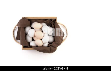 Chicken eggs are white and brown in a beautiful wooden package with a brown linen napkin. Stock Photo