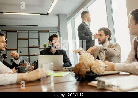 young confident men developing new business startup, discussing interaction in finance and market, sharing opinions and ideas with each other, dressed Stock Photo