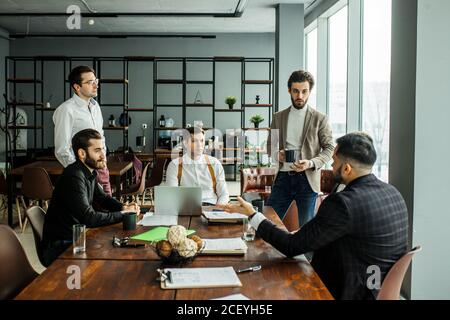 young caucasian business leaders gathered in office for coworking, hold meeting for discussion and having effective cooperation, everyone dressed in f Stock Photo