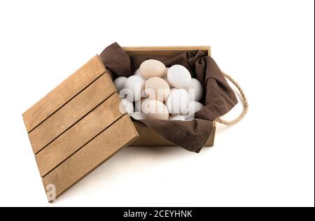 Fresh white and brown chicken eggs are placed in a wooden package with a lid. Stock Photo
