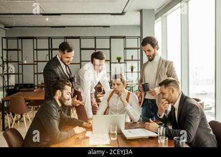 coworking of young business team gathered in office together, discussing and sharing opinons, wearing stylish formal clothes Stock Photo