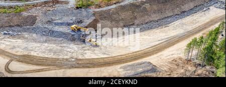 Panorama view from drone - excavator loads heavy stones and debris on industrial dump truck. Stones are from exploded mountain to free construction si Stock Photo