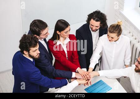 caucasian business team joining hands together in office, successful modern people in formal wear hold meeting in business room Stock Photo