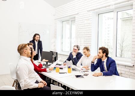 young caucasian people gathered in office to discuss business projects and ideas, wearing formal wear isolated in modern office. diverse enthusiastic Stock Photo