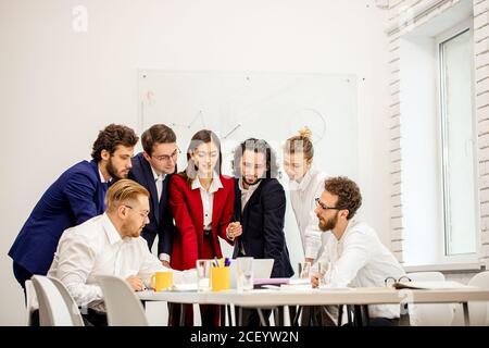 friendly business people co-working in modern office, enjoy working together, using laptop and having successful useful conversation, discussion Stock Photo
