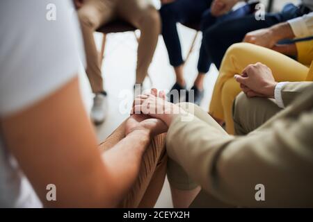 Business people after co-working sit in circle and hold hands together, hope for better work. office background Stock Photo