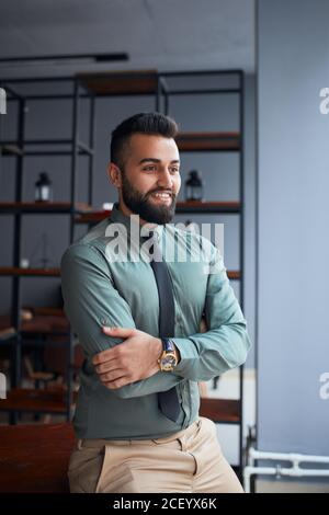 Smiling happy middle eastern businessman or leader standing in office and look side. successful team leader wearing formal wear shirt and tie, posing Stock Photo