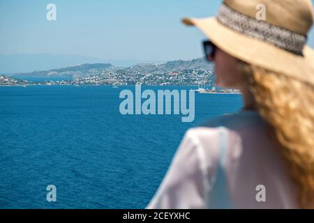 Beautiful sea view in resort hotel villa with blurred silhouette of woman in white dress sunglasses and bikini straw hat Stock Photo