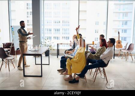 Young arabian business coach giving presentation to executive managers team explaining strategy in modern office, senior company leader presenting emp Stock Photo