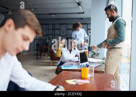 While working in office. Young business leaders sitting on table in the process of co-working, writing Stock Photo