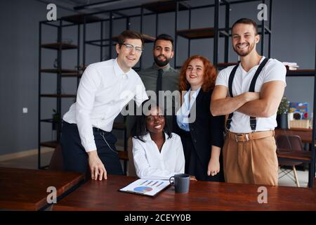 Cheerful multiracial team of male and female professionals posing in the office, career driven and successful corporate employees smiling and enjoying Stock Photo