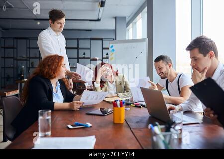 Young business people sad with result of their work, disappointed redhaired woman sit in the center of table Stock Photo