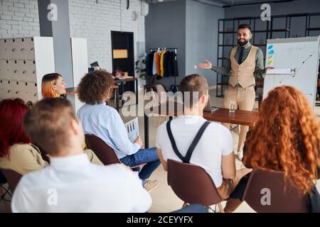 Young arabian business coach giving presentation to executive managers team explaining strategy in modern office, senior company leader presenting emp Stock Photo
