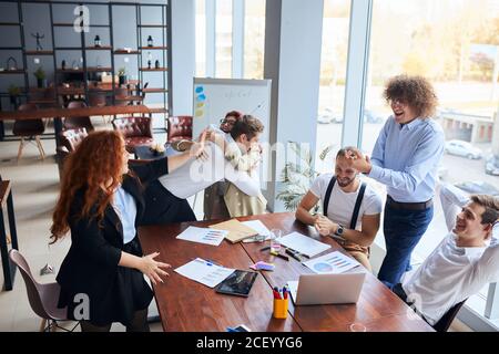 Everyday winners. Cheerful group of happy business people in formal wear looking at the laptop and gesturing, celebrate winning Stock Photo