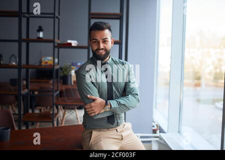 portrait of confident young handsome middle eastern businessman standing in office, looking at camera, successful team leader wearing formal wear, pos Stock Photo