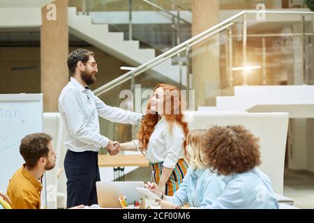 Decent, impressive middle aged manager friendly congratulates, young pretty female worker with successful job position, office work concept Stock Photo