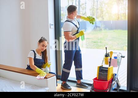 Smiling Professional Female Cleaners Washing Apartment With Rags