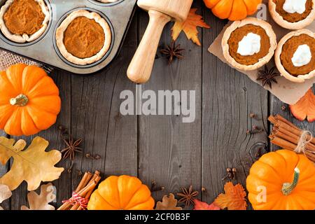 Autumn baking scene frame with pumpkin pie tarts, pumpkins, leaves and spices over a wood background Stock Photo