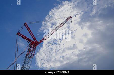 Nakano, Tokyo / Japan - July 26 2020: Looking up at a tall crane isolated against a partly cloudy sky in the late afternoon, with a crescent moon visi Stock Photo