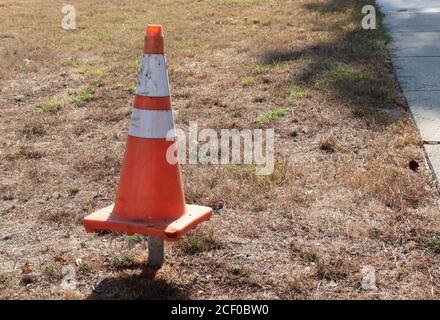 Bright orange traffic cone on a metal post in an empty park. Stock Photo