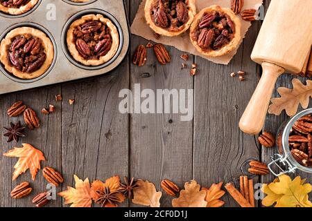 Autumn baking scene frame with pecan tarts, leaves and nuts over a wood background Stock Photo