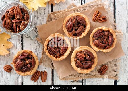 Mini pecan pie tarts, above view table scene on a rustic white wood background Stock Photo