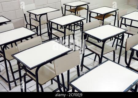 several tables and chairs in the classroom in an empty school without students Stock Photo