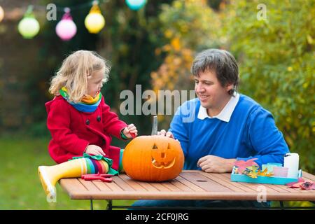 Family carving Halloween pumpkin. Parents and kids carve pumpkins for trick or treat lantern. Autumn activity for children. Father, mother, boy, girl Stock Photo