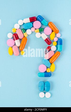 A question mark from laid out of medicine pills on blue background. Stock Photo