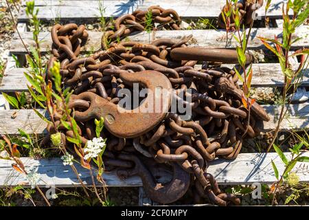 Old rusty chains rest on a wooden pallet. Stock Photo
