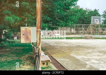 Old rusty electrical power control box on rusted electric pole in the public park. Stock Photo