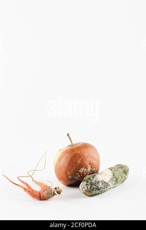 rotten apple, cucumber, carrot on white background. global hunger problem. overconsumption concept. top view copy space  Stock Photo