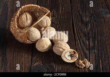 Walnut in basket and walnuts kernels on old wooden table Stock Photo
