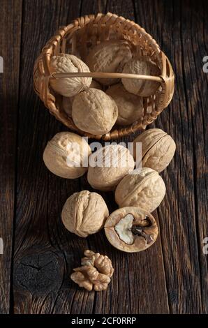 Walnut in basket and walnuts kernels on old wooden table Stock Photo