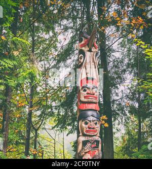 Alaska totem pole carving art sculture tourist travel destination forest background. Ketchikan, Juneau, Skagway, Vancouver. Stock Photo