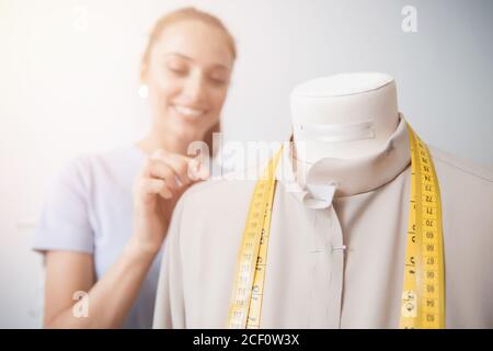 Seamstress fashion designer young woman works with mannequin, pins tailor with fabric for dress Stock Photo
