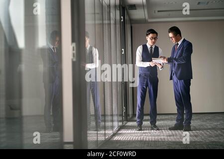 two asian corporate executives standing in office discussing business Stock Photo