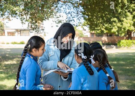 Jodhpur, Rajasthan, India - Jan 10th 2020: muslim teacher surrounded by students helping to solve their problem after school over while pointing in th Stock Photo