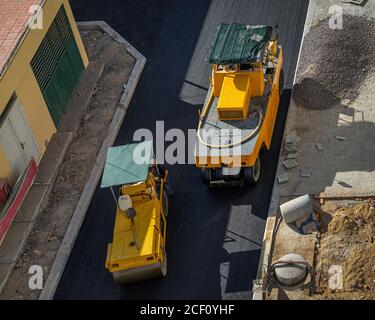 Asphalt road construction site with paving machine compacting asphalt. Pneumatic Tire Roller and Steel Wheel Roller at work.  View from above. Stock Photo