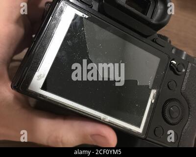 Camera with broken glass on the display in the hands of the repairer Stock Photo