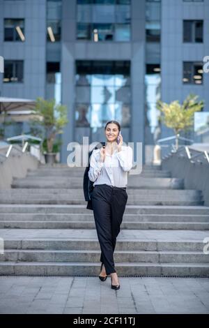 Slim elegant woman walking in the street and talking on the phone Stock Photo