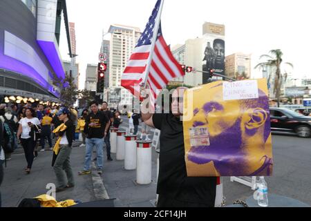 Los Angeles, CA, USA. 23rd Oct, 2020. A man holds an American flag and a Lebron James poster during a protest against China and a stand in solidarity with Hong Kong protesters. A man who goes by the alias Sun organized the event where shirts in support of Hong Kong protesters were handed out at the Staples Center. Stock Photo