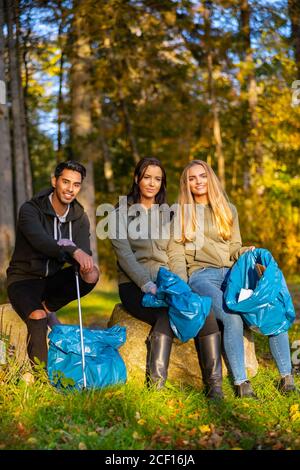 Female volunteers picking up garbage on grass Stock Photo