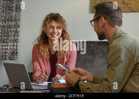 Businesswoman and businessman sitting at the table with laptop and discussing patterns in team at work Stock Photo