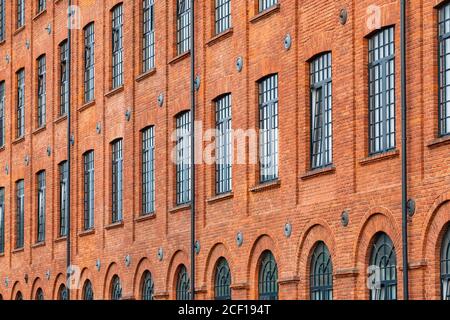 Red brick classic industrial building facade with multiple windows background. Stock Photo
