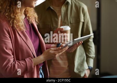 Close-up of two colleagues working online on digital tablet together at office Stock Photo