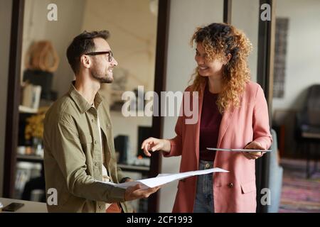 Two designers using tablet pc in work they standing and discussing blueprint at office Stock Photo