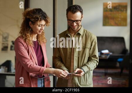 Two designers using digital tablet and discussing patterns for their new project while standing at office Stock Photo