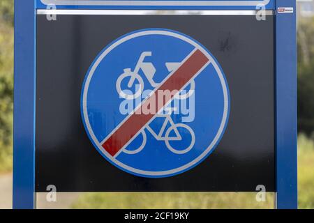 ALMELO, NETHERLANDS - Aug 02, 2020: Dutch traffic sign signifying the end of a bicycle and moped path with afoliage of trees in the background Stock Photo