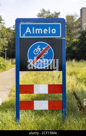 ALMELO, NETHERLANDS - Aug 02, 2020: Dutch traffic sign below entering the town of Almelo signifying the end of a bicycle path with foliage of trees in Stock Photo